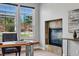 Bright office space with a natural wood desk, tiled fireplace, and large windows overlooking the yard at 6273 Torrey Ln, Arvada, CO 80403