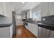 Modern kitchen featuring white cabinets, stainless steel appliances, black countertops, and hexagon backsplash at 716 S Osage, Denver, CO 80223