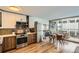 Modern kitchen with stainless steel appliances, wood cabinets, and a dining area with balcony access at 790 N Washington St # 1003, Denver, CO 80203