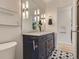 This bathroom features a double sink vanity, marble counters, black and white patterned floors and modern lighting at 3610 Olive St, Denver, CO 80207