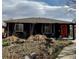 View of home exterior featuring a brown roof, black stucco, and an orange front door at 3610 Olive St, Denver, CO 80207