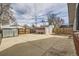 A large backyard concrete patio featuring sheds surrounded by bare trees and wooden fences at 828 S Osceola St, Denver, CO 80219