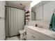 This bathroom offers an updated sink, mirror and shelving, and shower with green curtain at 701 Tucson, Aurora, CO 80011