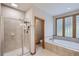 Spa bathroom with glass enclosed shower, soaking tub, and unique glass block window providing natural light at 31058 Big Bear Dr, Evergreen, CO 80439
