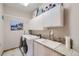 Bright laundry room featuring front load washer/dryer, tile countertops, and built-in storage cabinets at 31058 Big Bear Dr, Evergreen, CO 80439
