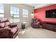 Bright living room with two large windows offering city views, comfortable armchairs, and a red accent wall at 925 N Lincoln St # 12G, Denver, CO 80203