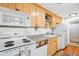 Efficient kitchen with light wood cabinets, white appliances, and open shelving above the countertop at 148 S Emerson St # 206, Denver, CO 80209