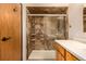 Tiled shower in bathroom with glass sliding door and white countertop vanity with wood cabinets at 3525 S Brentwood St, Lakewood, CO 80235