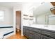 Bathroom with updated dual sink vanity, wood floors, and decorative shelving at 13812 W 64Th Pl, Arvada, CO 80004