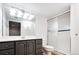 This bathroom features gray cabinets, granite countertop, tile flooring, and a glass-doored shower at 13812 W 64Th Pl, Arvada, CO 80004