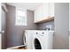 Laundry room features a window, overhead storage, and modern washer and dryer at 13812 W 64Th Pl, Arvada, CO 80004