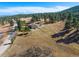 Aerial view of a home nestled in a wooded landscape, accessible by a winding road at 87 Elmgreen Ln, Evergreen, CO 80439