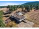 Expansive aerial view of the property showcasing the house, outbuilding, and surrounding wooded landscape at 87 Elmgreen Ln, Evergreen, CO 80439