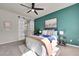 Modern bedroom featuring a teal accent wall, barn door to bath, and ceiling fan at 5179 S Fairplay St, Aurora, CO 80015