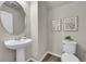 Modern powder room with a pedestal sink, decorative mirror, and neutral wall color with framed artwork at 5179 S Fairplay St, Aurora, CO 80015