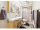 Well-lit bathroom with modern sink, wood cabinet, sliding glass shower door, and neutral tile flooring at 8460 Corona St, Denver, CO 80229