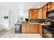 Well-lit kitchen features wood cabinets, granite counters and black appliances at 8460 Corona St, Denver, CO 80229