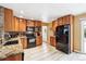 Modern kitchen featuring warm wood cabinetry, stone countertops, black appliances, and sleek light flooring at 8460 Corona St, Denver, CO 80229
