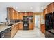 Modern kitchen featuring warm wood cabinetry, stone countertops, and black appliances and light flooring at 8460 Corona St, Denver, CO 80229