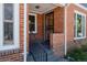 Close-up of the front entrance with brick siding, black railings, and a secure screen door at 3055 Clermont St, Denver, CO 80207