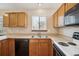 Well-lit kitchen features a stainless steel sink, black dishwasher, and plentiful wooden cabinets at 11908 W Aqueduct Dr, Littleton, CO 80127