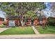 Inviting brick home with lush front yard, charming porch, and driveway leading to a detached garage at 1320 Quari St, Aurora, CO 80011