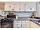 Bright kitchen featuring white cabinets, brick backsplash, granite counters and black appliances at 10743 W Berry Pl, Littleton, CO 80127