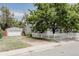 Charming home exterior with a white picket fence, detached garage, and mature tree at 1200 S Patton Ct, Denver, CO 80219