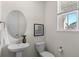 Cozy half bath with a pedestal sink, oval mirror, and a bright window at 455 N Old Hammer St, Aurora, CO 80018