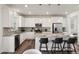 Well-lit kitchen featuring white cabinets, stainless appliances, a large island with bar seating, and hardwood floors at 455 N Old Hammer St, Aurora, CO 80018