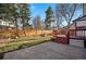 Spacious backyard with a wooden fence, red deck, mature trees, and a concrete patio, perfect for outdoor activities at 15974 E Loyola Dr, Aurora, CO 80013