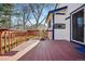 Inviting backyard featuring a wooden deck with red railings, partially shaded by mature trees and blue sky at 15974 E Loyola Dr, Aurora, CO 80013