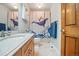 Charming bathroom featuring a whale-themed shower curtain, tiled floor, and a wood-finished vanity at 15974 E Loyola Dr, Aurora, CO 80013