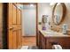 Bathroom features a marble countertop vanity, decorative mirror, and an adjacent room with hardwood floors at 15974 E Loyola Dr, Aurora, CO 80013