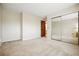 Well-lit bedroom featuring mirrored closet doors, neutral carpet, and access to the hallway for easy flow at 15974 E Loyola Dr, Aurora, CO 80013