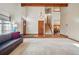 Open-concept living room with a high ceiling, wood beam, carpeted flooring, wood stairs, front door, and a gray sofa at 15974 E Loyola Dr, Aurora, CO 80013