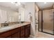 Well-lit bathroom with double sinks, granite countertops, and a glass door shower at 4739 Raven Run, Broomfield, CO 80023