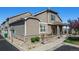 Townhome featuring stone accents, tan siding, attached garage, covered porch, and well-manicured landscaping at 4739 Raven Run, Broomfield, CO 80023