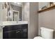 Well-lit half bathroom with a black vanity, toilet, and a decorative mirror at 10788 Ventura St, Commerce City, CO 80022