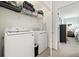 Functional laundry room equipped with modern washer and dryer units and storage shelves at 10788 Ventura St, Commerce City, CO 80022