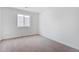An empty bedroom featuring a large window for natural lighting and neutral carpet at 9092 Telluride Ct, Commerce City, CO 80022