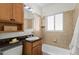Bathroom features a bathtub and shower combo, vanity with wooden cabinets, and tiled walls at 1177 Wabash St, Denver, CO 80220