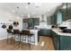 Bright kitchen with stainless steel appliances, dark green cabinets, white marble backsplash, and island with barstool seating at 3444 Recess Pt, Castle Rock, CO 80108