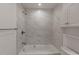 Bright bathroom featuring a shower and tub combination with gray and white marbled tile and white vanity with storage at 3360 Magnolia St, Denver, CO 80207