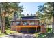 A beautiful two-story brick home with a large wooden deck surrounded by mature trees at 25357 Snyder Ave, Conifer, CO 80433