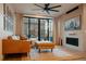 Cozy living room featuring a brick fireplace, leather couch, a modern ceiling fan, and large windows at 527 Fox St, Denver, CO 80204