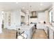 Modern kitchen boasts white cabinetry, stainless steel appliances, large marble island, and stylish pendant lighting at 7952 Dante Dr, Littleton, CO 80125