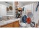 Updated bathroom with single sink vanity, granite countertops, shelving, and a floral design shower curtain at 19707 E 59Th Pl, Aurora, CO 80019