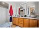 Bathroom with double vanity, wood cabinets, a shower with white curtain, and a red towel hanging on the wall at 19707 E 59Th Pl, Aurora, CO 80019