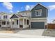 Two-story home featuring a charming front porch, gray siding, well-manicured landscaping, and an attached two-car garage at 190 Lark Sparrow Way, Bennett, CO 80102